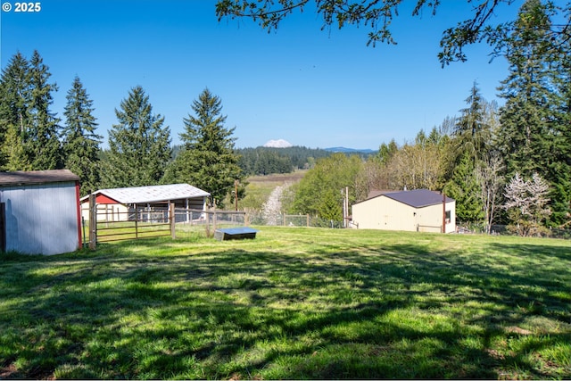 view of yard with an outbuilding, a pole building, and a wooded view