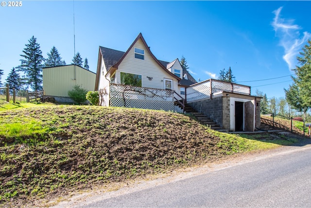 view of property exterior featuring stairs, a wooden deck, and fence