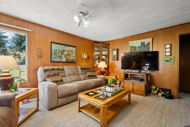 living area featuring healthy amount of natural light, carpet flooring, and wood walls