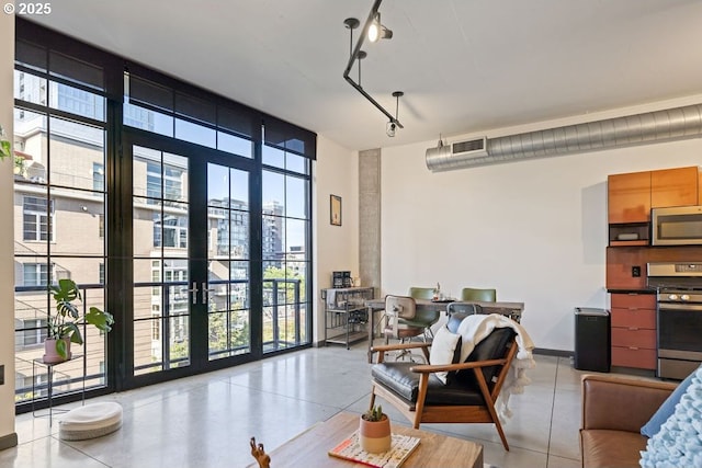 interior space featuring baseboards, visible vents, a wall of windows, french doors, and track lighting