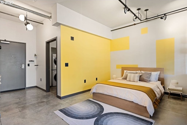 bedroom featuring stacked washer and clothes dryer, finished concrete flooring, and baseboards