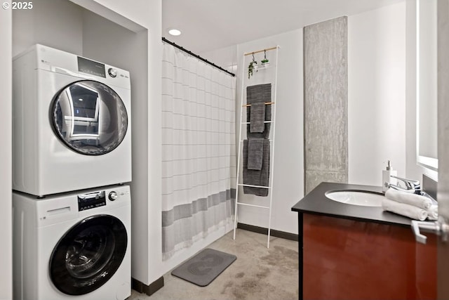 washroom with laundry area, stacked washer and dryer, a sink, and baseboards