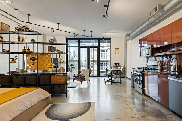 bedroom featuring a sink, finished concrete flooring, french doors, floor to ceiling windows, and rail lighting