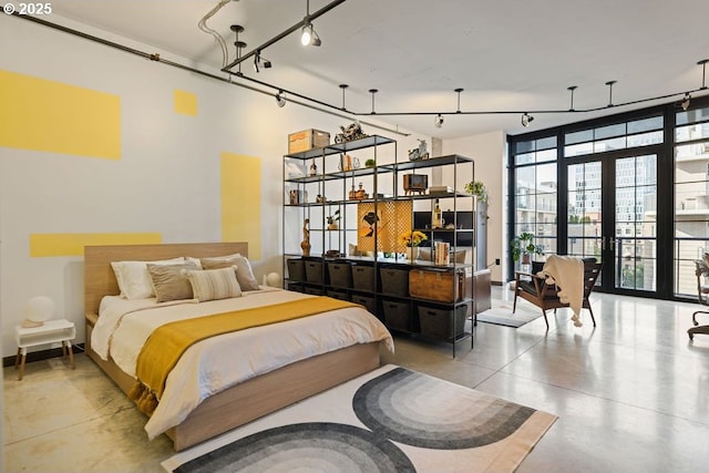 bedroom with rail lighting, concrete floors, and french doors