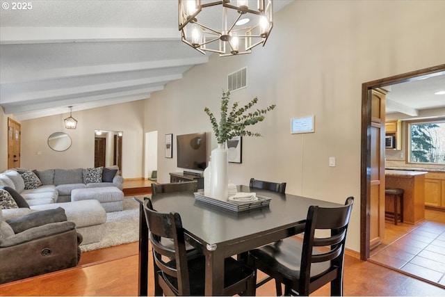 dining space with high vaulted ceiling, beam ceiling, a chandelier, a textured ceiling, and visible vents