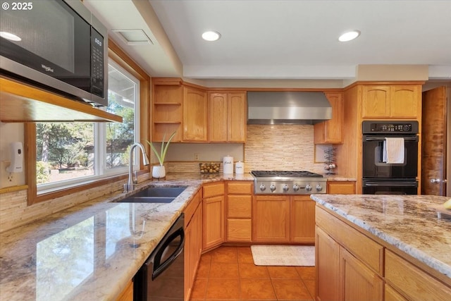 kitchen featuring light stone counters, a sink, wall chimney exhaust hood, light tile patterned floors, and black appliances