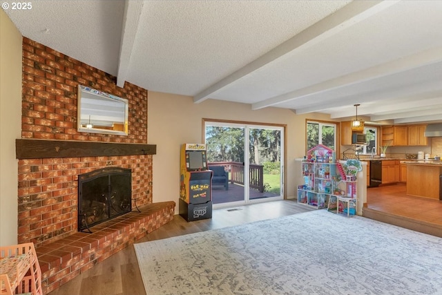 living area featuring a brick fireplace, beamed ceiling, light wood-style flooring, and a textured ceiling