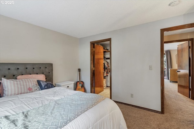 carpeted bedroom with a spacious closet, a closet, and baseboards