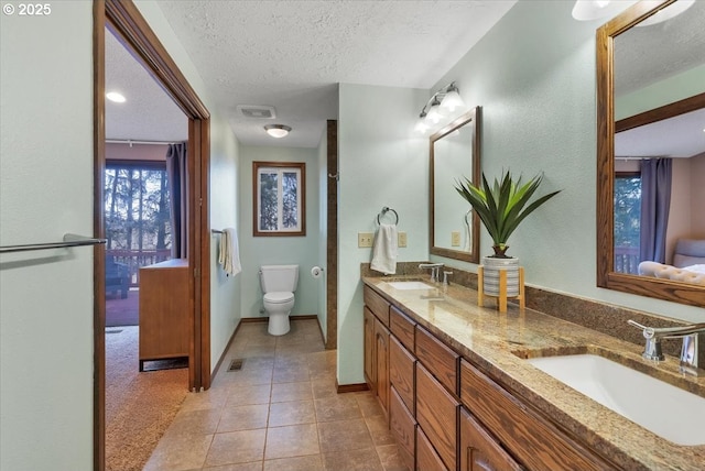 full bath featuring double vanity, a sink, tile patterned flooring, and a textured ceiling