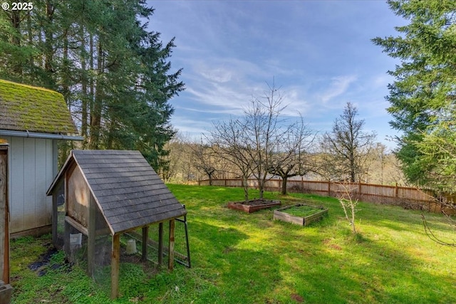 view of yard with a garden, an outbuilding, and fence