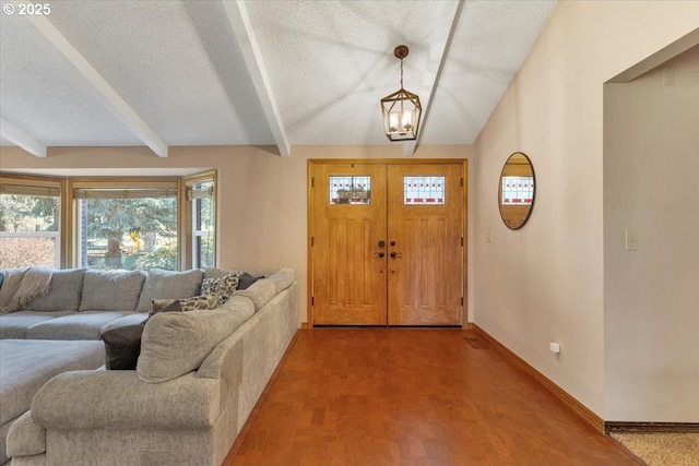 foyer entrance featuring wood finished floors, vaulted ceiling with beams, baseboards, and a textured ceiling