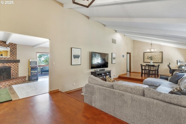 living area with vaulted ceiling with beams, a fireplace, baseboards, visible vents, and an inviting chandelier