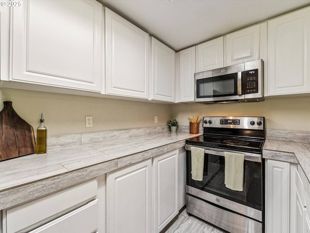 9908 SE Talbert St, Clackamas, OR 97015 - kitchen featuring appliances with stainless steel finishes, white cabinetry, and light countertops