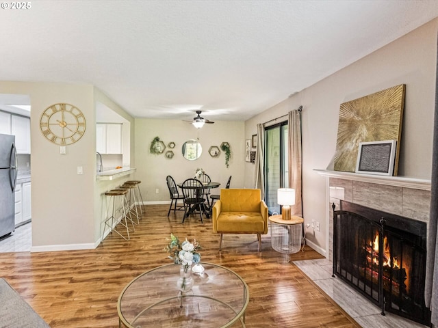 9908 SE Talbert St, Clackamas, OR 97015 - living room featuring a ceiling fan, light wood-style flooring, and a tile fireplace