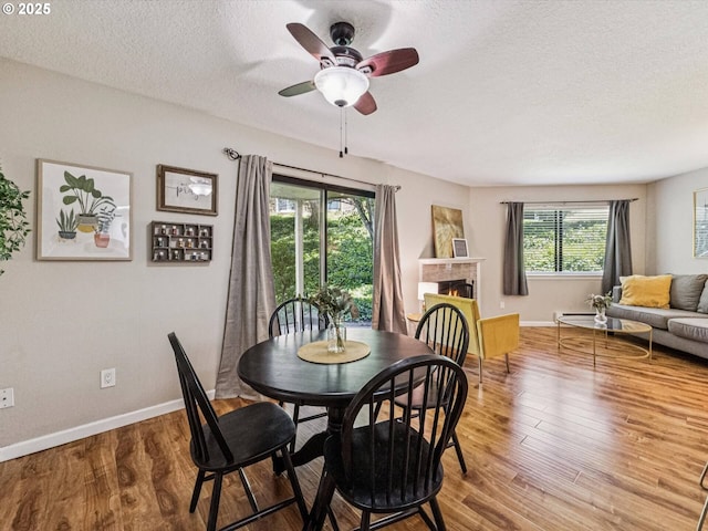 9908 SE Talbert St, Clackamas, OR 97015 - dining space featuring a textured ceiling, wood finished floors, ceiling fan, and a lit fireplace