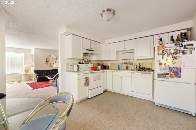 kitchen featuring white appliances, under cabinet range hood, a sink, white cabinets, and a textured ceiling
