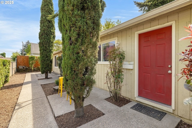 entrance to property featuring fence and a patio