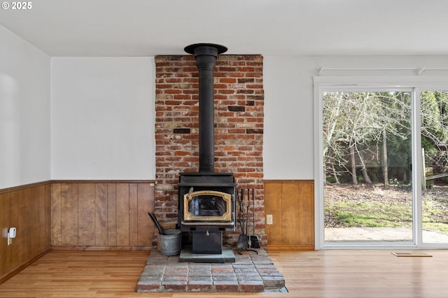 unfurnished living room with wooden walls, light hardwood / wood-style floors, and a wood stove