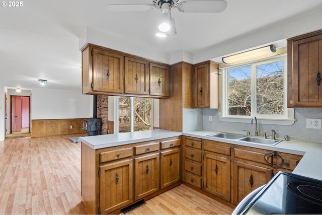 kitchen with sink, ceiling fan, light hardwood / wood-style floors, decorative backsplash, and kitchen peninsula