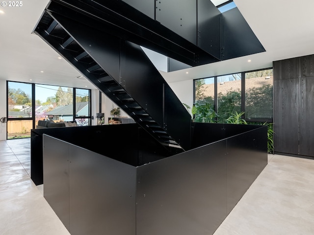stairway with recessed lighting, a wall of windows, and concrete floors