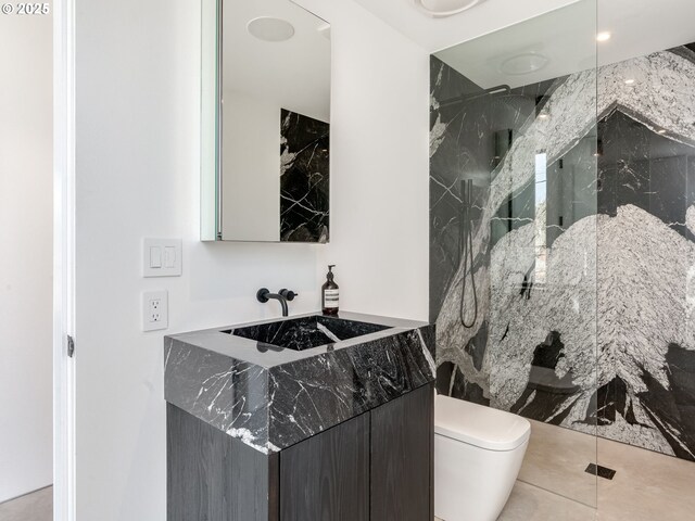 bathroom featuring a marble finish shower, toilet, and vanity