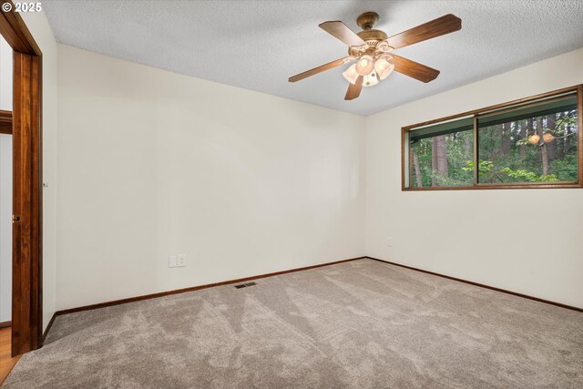 carpeted empty room with baseboards, ceiling fan, and a textured ceiling