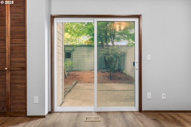 doorway to outside featuring baseboards and wood finished floors