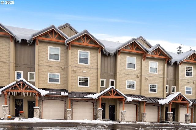 townhome / multi-family property with a garage, a standing seam roof, metal roof, and stone siding