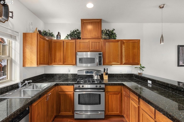 kitchen featuring tile countertops, appliances with stainless steel finishes, brown cabinetry, and a sink