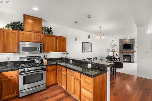 kitchen featuring a peninsula, dark wood-style flooring, stainless steel appliances, and tile countertops