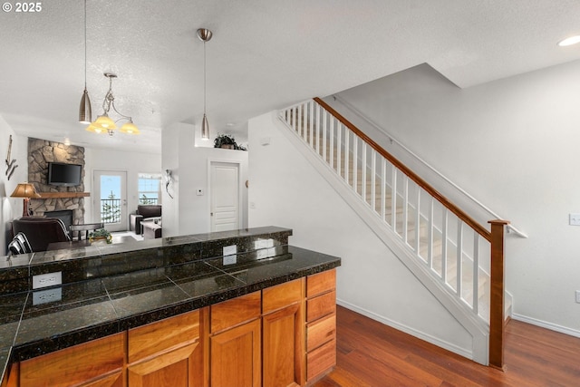 kitchen featuring pendant lighting, open floor plan, tile counters, dark wood-type flooring, and a textured ceiling