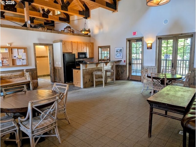 dining area featuring wainscoting, light carpet, and high vaulted ceiling