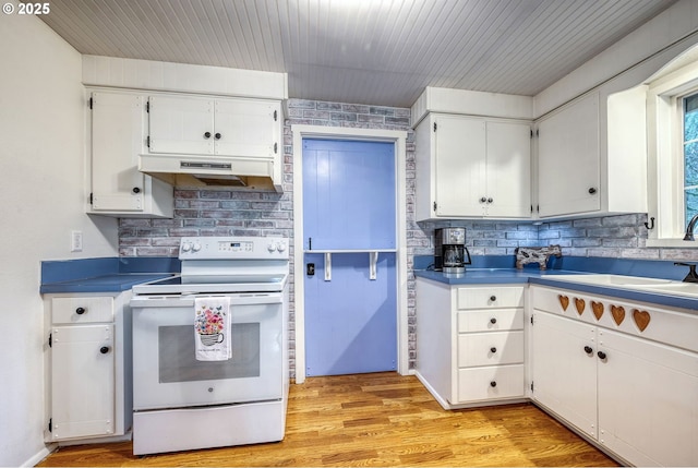 kitchen with under cabinet range hood, light wood-type flooring, electric stove, white cabinets, and a sink