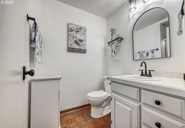 bathroom featuring vanity, toilet, and baseboards