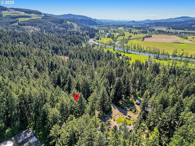 birds eye view of property featuring a water and mountain view and a wooded view