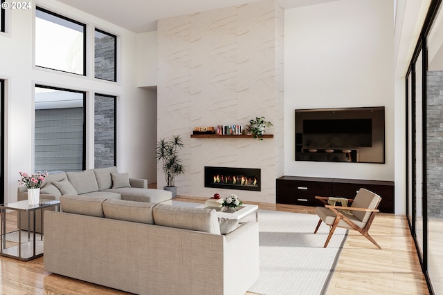 living room with light wood finished floors, a high ceiling, and a high end fireplace