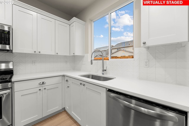 kitchen with backsplash, stainless steel appliances, white cabinetry, and sink