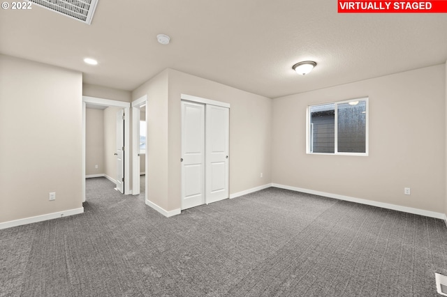 unfurnished bedroom featuring a closet and dark colored carpet