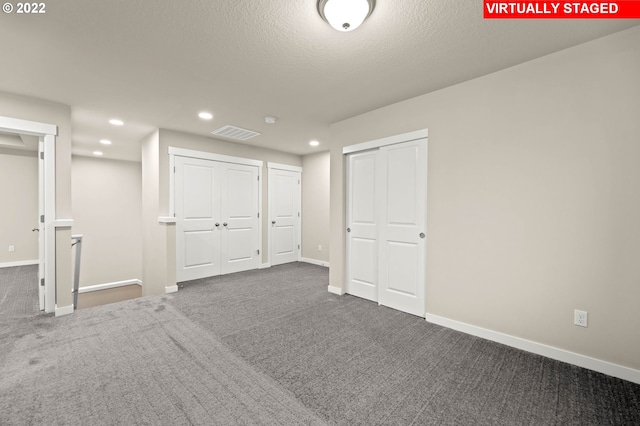 interior space featuring a textured ceiling and dark carpet