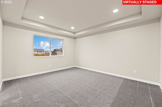 carpeted spare room featuring a tray ceiling