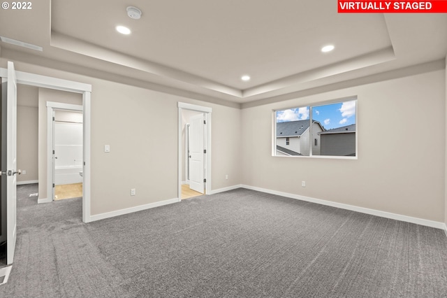 interior space with a tray ceiling and carpet flooring