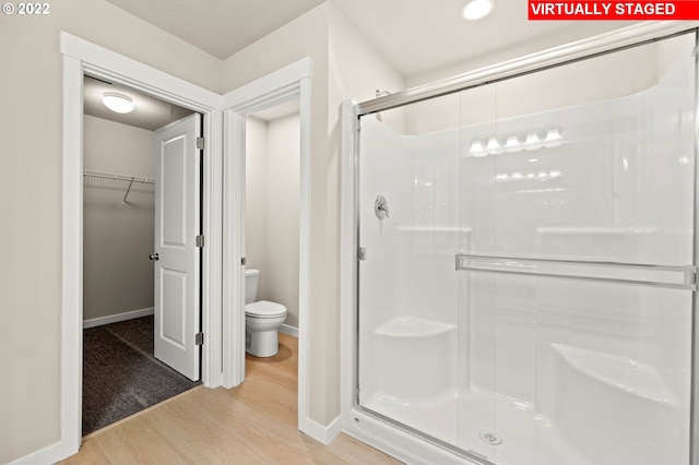 bathroom with wood-type flooring, an enclosed shower, and toilet