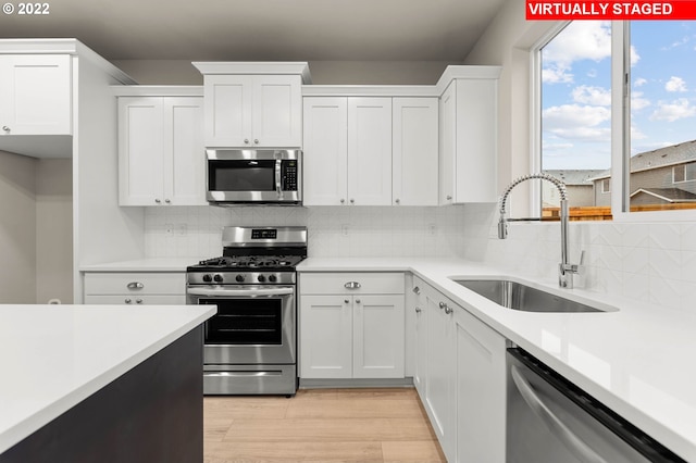 kitchen with appliances with stainless steel finishes, tasteful backsplash, white cabinetry, and sink