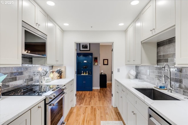 724 NW Westover Cir, Portland, OR 97210 - kitchen featuring appliances with stainless steel finishes, a sink, decorative backsplash, light wood finished floors, and recessed lighting
