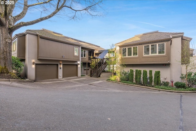 724 NW Westover Cir, Portland, OR 97210 - view of front of property with stairs, a garage, asphalt driveway, a tiled roof, and stucco siding