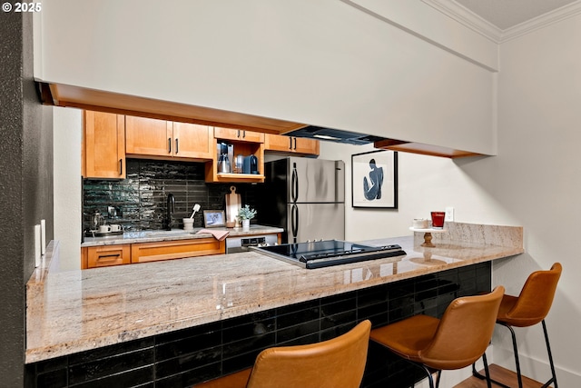 kitchen with a sink, a peninsula, crown molding, and freestanding refrigerator