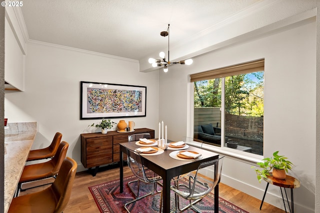 dining room featuring baseboards, light wood-style floors, an inviting chandelier, and crown molding