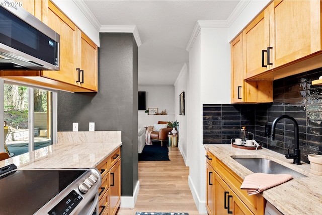 kitchen featuring ornamental molding, decorative backsplash, light wood-style floors, stainless steel appliances, and a sink