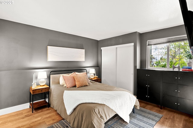 bedroom featuring baseboards, a closet, and light wood finished floors