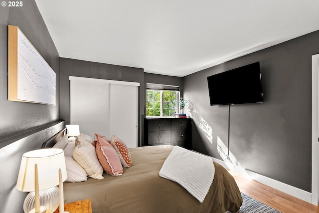 bedroom with baseboards, wood finished floors, and a textured wall